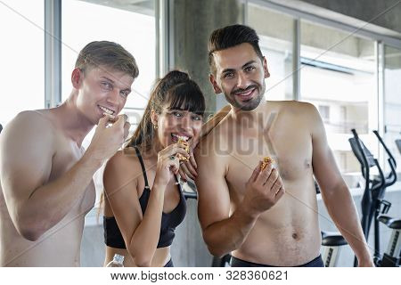 Groups Of Caucasian Sporty Man And Woman Enjoy Eating Snack Bar Resting After Workout. Energy Food A