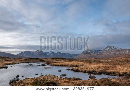 Brown Wintery Grass Fields Overlooking Black Mount Mountain Range On A Partially Cloudy Day In The S