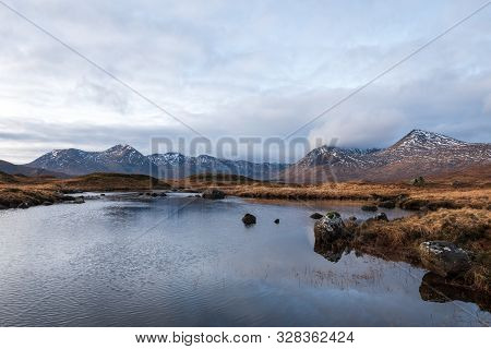 Brown Wintery Grass Fields Overlooking Black Mount Mountain Range On A Partially Cloudy Day In The S