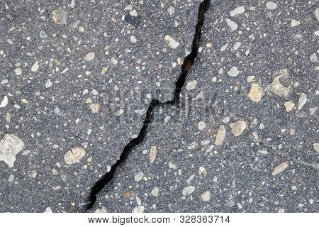 Vertical Broken Crack On The Surface Of Asphalt Pavement. The Crack Is Diagonal And Bisects. Gray As