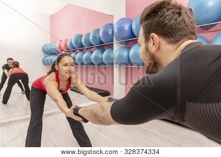 Portrait Of A Young Woman With Braces Doing Stretching Exrcises In A Gym Together With Her Boyfriend