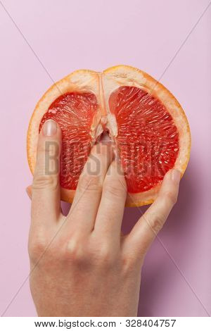 Two Female Fingers In Grapefruit, Woman Masturbation And Sex Concept. Vagina And Clitoris Symbol.