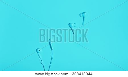 Wireless In Ear Headphones And Cable Earphones On Blue Background Close Up. Minimal Music Concept. W