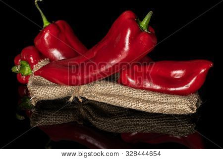 Group Of Four Whole Sweet Red Bell Pepper With Jute Bag Isolated On Black Glass