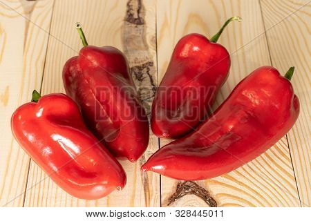 Group Of Four Whole Sweet Red Bell Pepper On Natural Wood