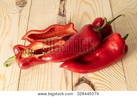 Group Of Three Whole Two Halves Of Sweet Red Bell Pepper On Natural Wood
