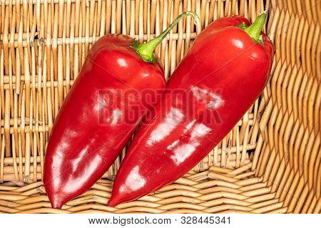 Group Of Two Whole Sweet Red Bell Pepper With Braided Rattan Behind