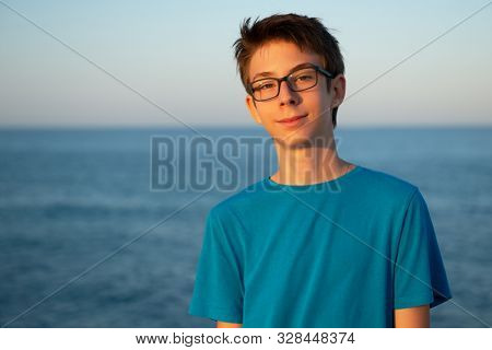 Handsome young boy at beach in Alicante. Beautiful calm smiling teen boy at Mediterranean sea coast in Spain. Travel, summer vacation, tourism, teenage lifestyle.