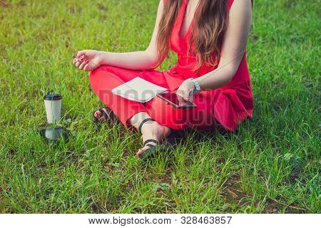 Cropped No Face Young Businesswoman In Red Suit Sitting In Lotus Position On Green Grass In Park And