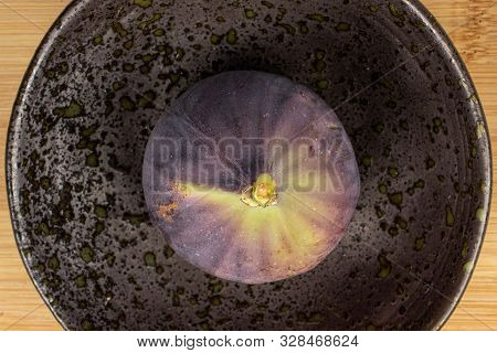One Whole Sweet Purple Fig On Glazed Bowl Flatlay On Light Wood