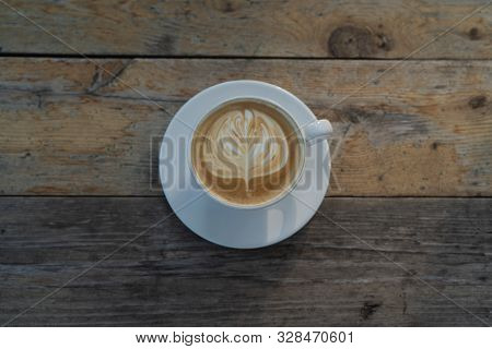 Cup Of Coffee With Latter Art Sitting On A Wooden Table