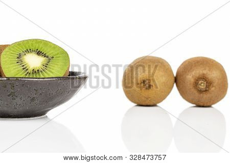 Group Of Two Whole One Half Of Exotic Brown Kiwi On Glazed Bowl Isolated On White Background