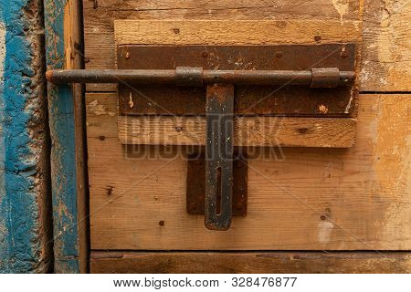 An Old Corroded Latch Of A Ragged Wooden Door