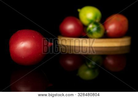 Group Of Five Whole Fresh Tomato De Barao On Round Bamboo Coaster Isolated On Black Glass
