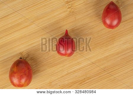 Group Of Three Whole Fresh Tomato De Barao Flatlay On Light Wood