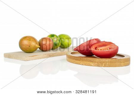 Group Of Four Whole Two Halves Of Fresh Tomato De Barao On Wooden Cutting Board On Round Bamboo Coas