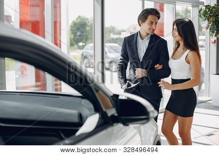 Stylish And Elegant Couple In A Car Salon