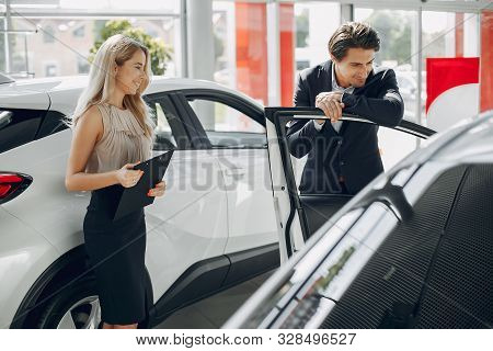 Stylish And Elegant Couple In A Car Salon