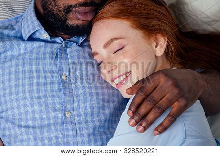 Ginger Hair European Female And Handsome Afro African Male Together Hugging Lying In Bedroom At Home