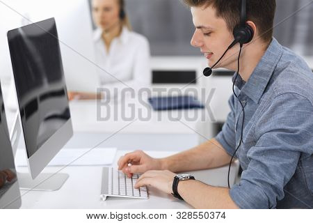 Call Center. Group Of Casual Dressed Operators At Work. Focus On Young Businessman In Headset At Cus