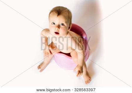 Baby Girl Sits On A Childrens Pot, Toilet On A White Background