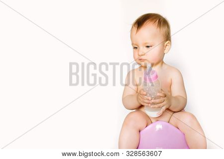 Charming Photo Of Cute Baby Girl Holding A Boottle With Baby Milk And Sitting On A Pink Potty. Isola