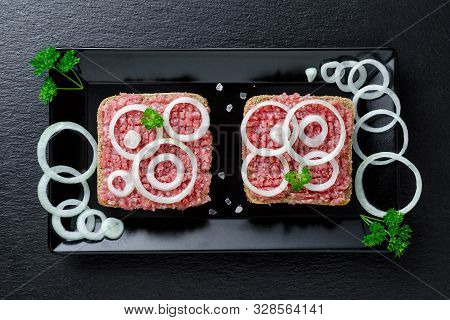 German Food Mett Ground Pork, Bun And Raw Meat With Onion And Parsley On Black