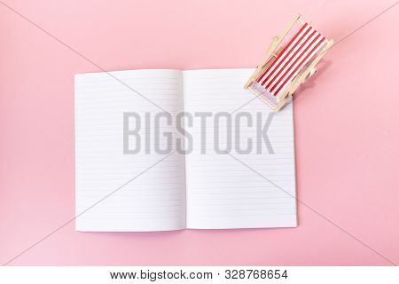 Blank Opened Notebook With A Model Of A Desck Chair On Pink Background. Vacation Planning Concept. T