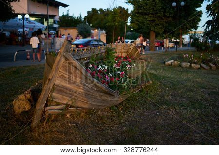 Old Wooden Boat As A Decoration (flowerbed With Flowers) On The Streets Of The Seaside Town. Pomorie
