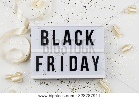 Black Friday Sale Text On White Lightbox, Golden Stars And Holiday Ribbon Around On White Background