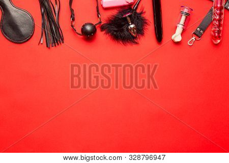 Bdsm Kit From Sex Shop. Leather Whip, Buttplug, Vibrator, Dildo, Gag And Other On Red Background. Fr