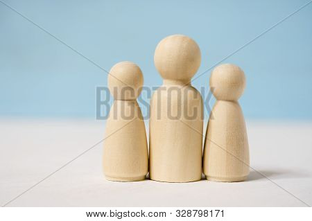 Close Up Of Wooden Figures Of Man With Two Woman Or Adult With Two Children.