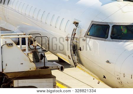 Jet Engine Against A Middle Size Plane At The Airport On Loading Aircraft At The International Airpo