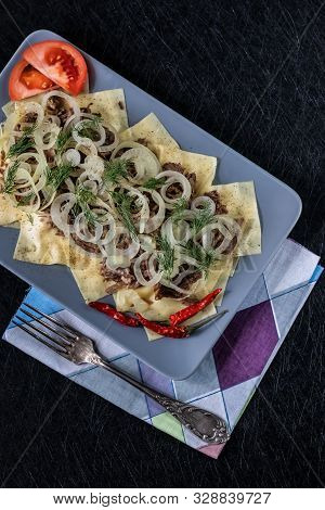 Beshbarmak Is A National Kazakh Dish - Square Pasta With Boiled Meat And Onions. On A Black Backgrou