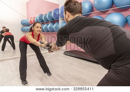 Portrait Of A Young Woman With Braces Doing Stretching Exrcises In A Gym Together With Her Boyfriend