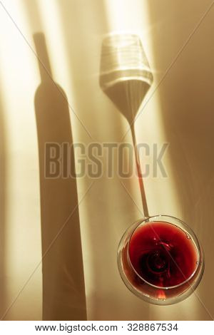 A Spectacular Long Shadow Falls From The Glass With Wine, Next To It Is The Shadow Of A Bottle Of Wi