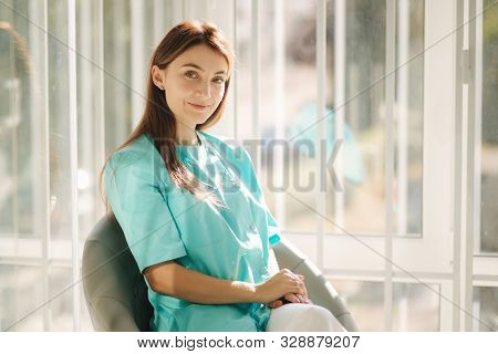 Female Cosmetologist In Green Robe. Beautiful Doctor In Beauty Salon
