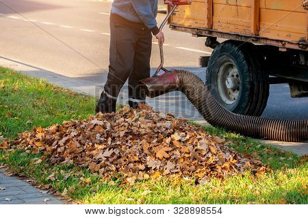 Worker Clearing Up The Leaves Using A Leaf Blower Tool
