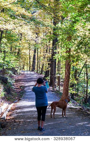Pittsburgh, Pennsylvania, Usa 10/20/2019 A Woman And Her Dog Stopping To Take A Picture Along A Walk