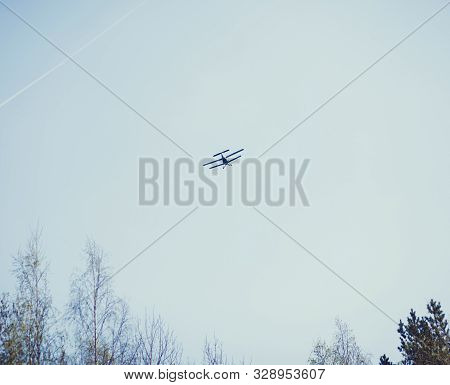 A Small Plane Flies High Above The Trees