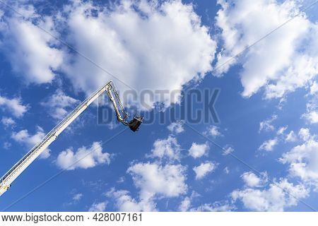 Car Tower For Lifting People To A Great Height On The Background Of The Blue Sky.