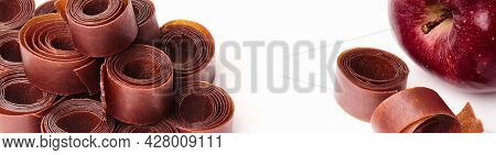 Rolls Of Fruit Leather And Apple On White Surface