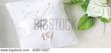 Banner With White Rose And Pillow With Rhinestone Hearts For Wedding Rings With Rings On White Backg