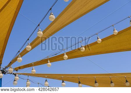 Dynamic Airy Texture Of Yellow Fabric Stretch Roof Made Of Canvas Sail With Rows Of Bulb Lamps For P