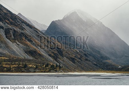 Gloomy Autumn Foggy View To Gray Mountain Lake And Rocky Pinnacle With Snow On Top In Haze In Rainy 