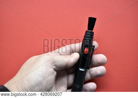 Brush For Cleaning Optics On A Red Background