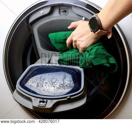 Function Adding Laundry During Washing. A Person Puts Clothes In The Washing Machine. House Cleaning
