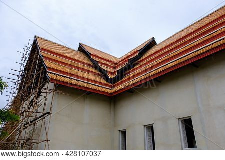 The Unfinished Traditional Thai Church With The Wooden Scaffolding Beside The Cement Wall, In The Lo