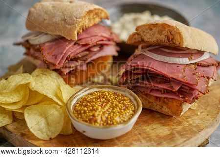 Pastrami sandwhich with delicious meet on baguette bread with chedder cheese, onion