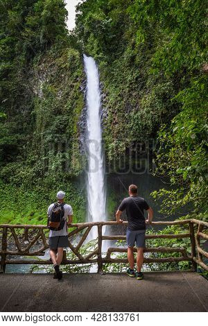 Two Tourists Looking At The La Fortuna Waterfall In Costa Rica